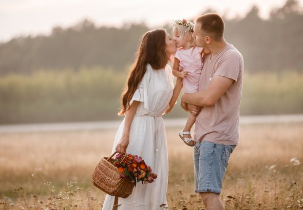 Retrato de familia feliz. Mamá, papá e hija pasean por el campo. Familia joven pasando tiempo juntos de vacaciones, al aire libre.