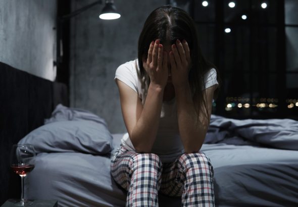 Mujer joven que se cubre la cara con las manos, pasa la noche en vela, se siente desamparada y llora.