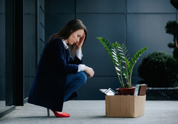 Una mujer estresada sentada entre cajas de cartón.